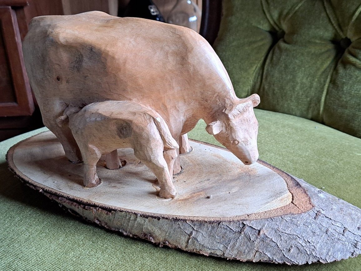 Carving of a cow and calf standing on a slice of log