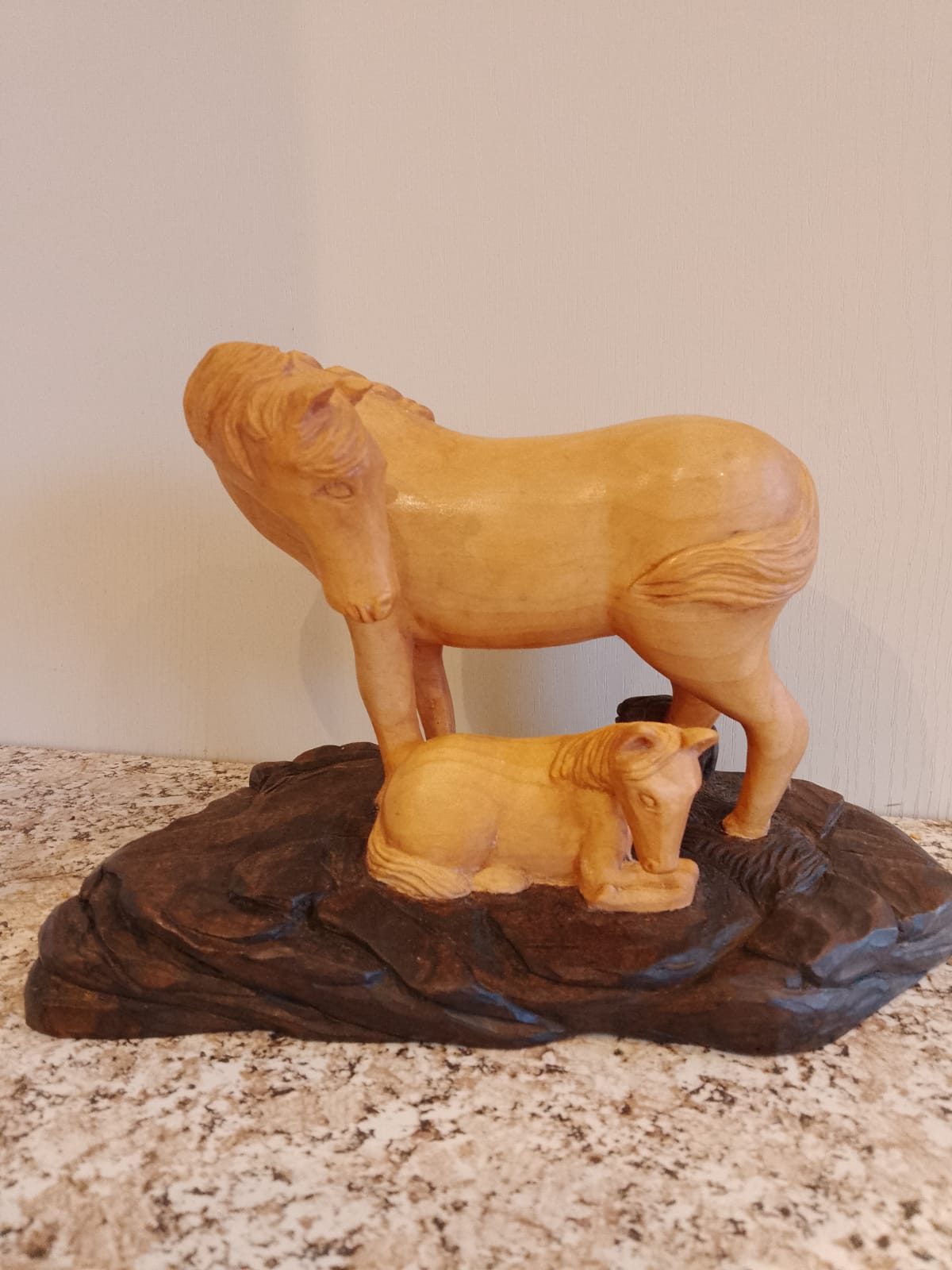 Carved mare standing over a lying foal on a dark base