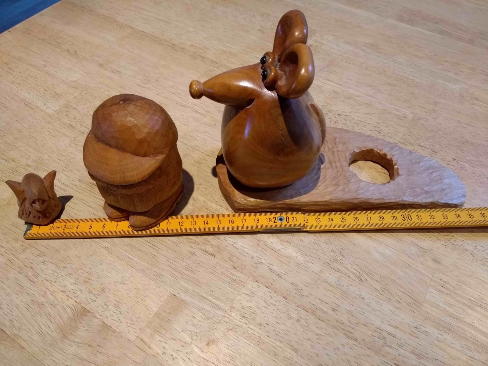 Large carved mouse with big ears on a wedge of cheese, beside two small carved figures and a folding rule