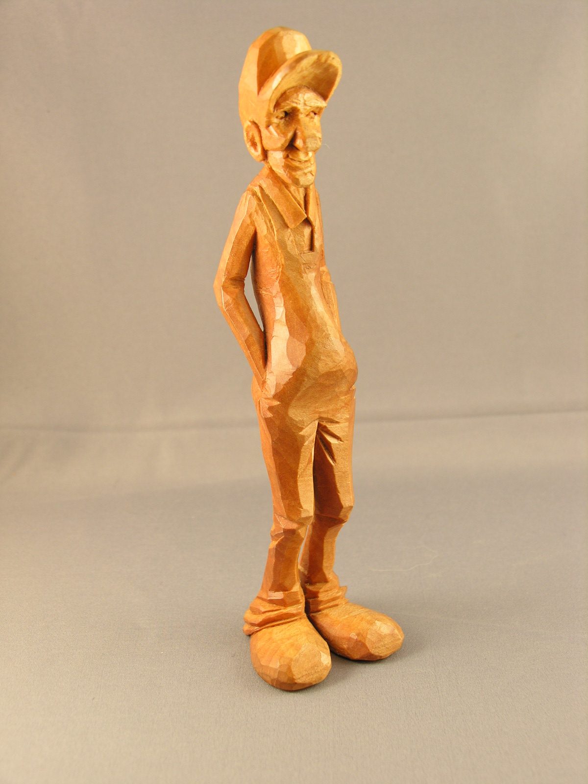 Caricature figure of a man in a cap, standing with his hands in his pockets